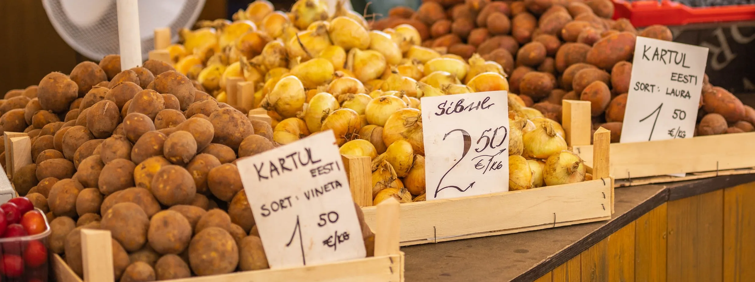 erinevad kartulisordid ja sibulad turuletilil kastide sees juures hinnasildid koos päritolumaa infoga "Ees